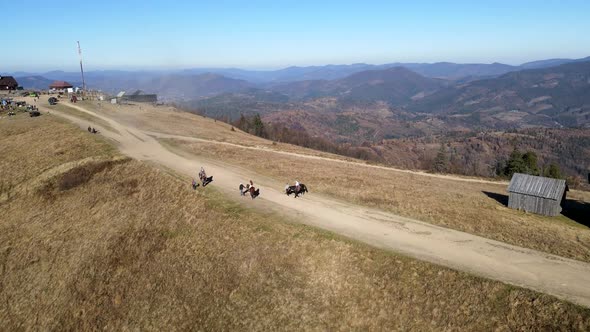 Aerial View People Riding Horse Attraction at the Top of Mountain alt