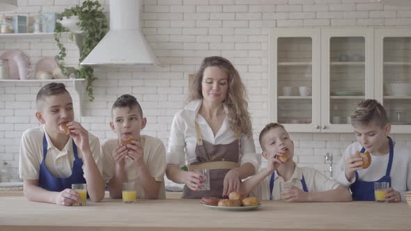 Portrait Attractive Happy Woman and Her Four Teen Son Eating Pies and Drinking Orange Juice in the alt