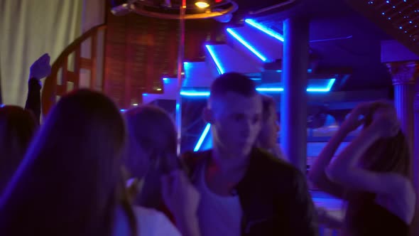 A group crowd of people dancing on the dance floor in a nightclub. alt