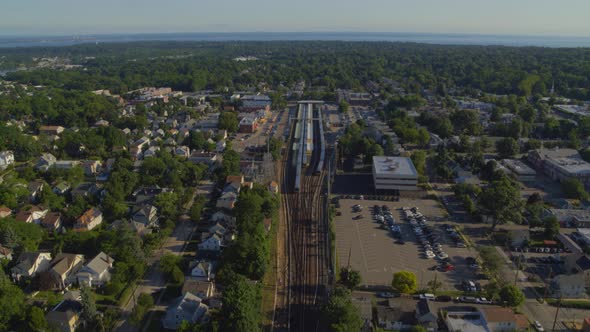 Train Stopped at Station and Small Town in Long Island Aerial View alt