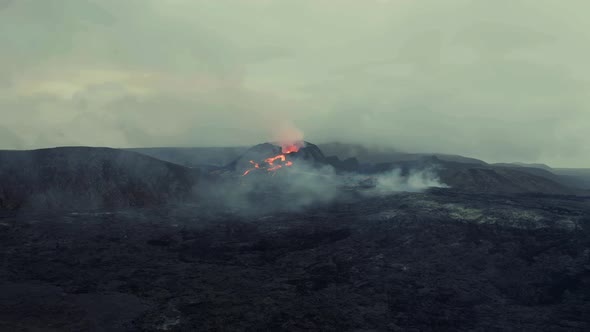 Drone shot towards magma fields and erupting craters in gloomy Iceland - approaching, Aerial view alt