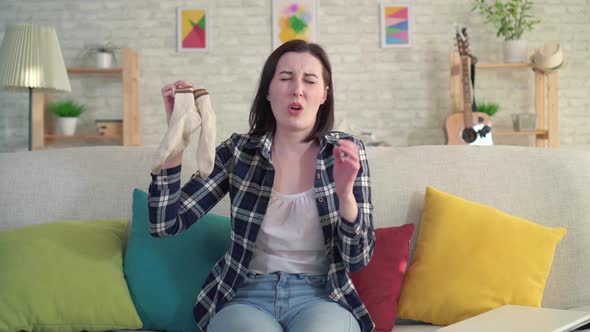 Young Woman Holds Socks in Her Hands and Feels an Unpleasant Smell alt
