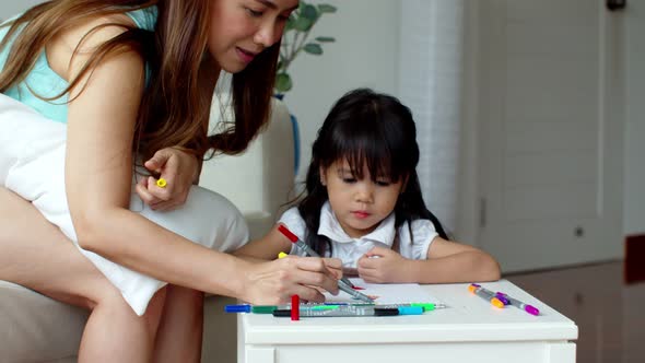 Mother and daughter enjoy to paint colour pencil on paper alt