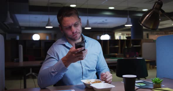 Businessman working and eating in a modern office by night alt