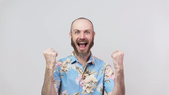 Happy man wearing hawaiian shirt celebrating a victory over white background. Emotions of success