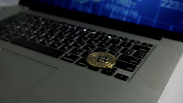 Dolly shot of Bitcoin BTC cryptocurrency. Golden coin on laptop keyboard alt