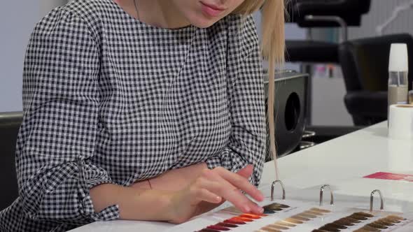 Woman Choosing Hair Color From Dye Chart at Hairdresser Salon alt