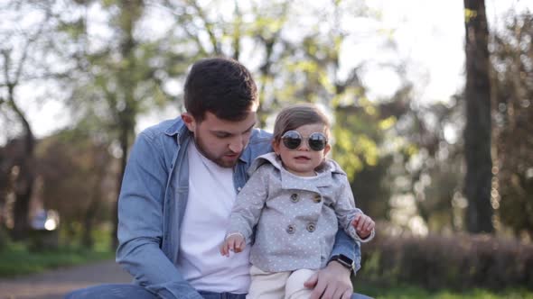 Dad Put on Sunglasses To His Little Daughter in Suuny Day alt