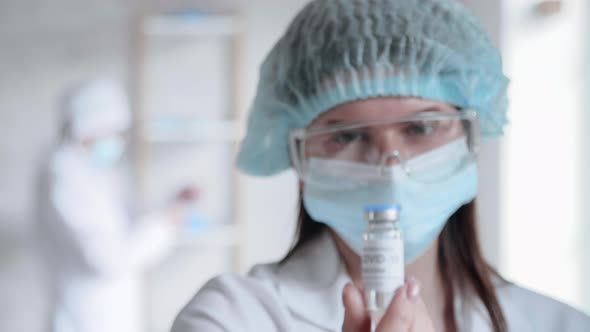Doctor in Protective Glasses Looks Onto the Tubes alt