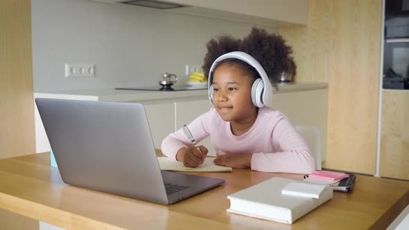 Little African American Girl Studying From Home Answering During Online Lesson alt