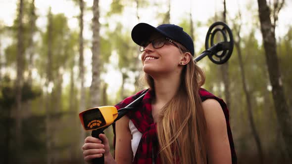 Young Happy Woman in the Forest with the Metal Detector on Her Sholder alt