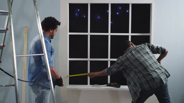AfricanAmerican Man Measures Window Length with Colleague alt