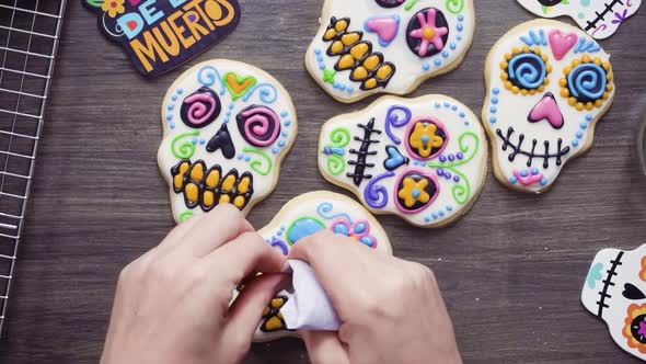 Step by step. Flat lay. Decorating sugar skull cookies with different color royal icing. alt
