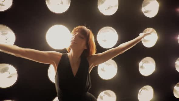 Beautiful woman dancing in front of a wall of lights alt