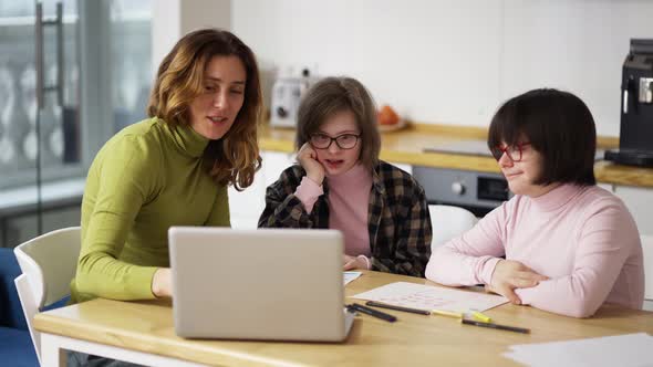 Teacher Teaches Young Girls with Down Syndrome to Use a Laptop alt