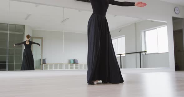 Caucasian female ballet dancer practicing ballet during a dance class in a bright studio alt