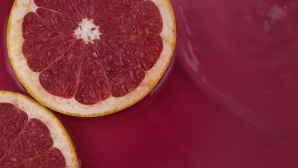 Juicy Pieces of Fresh Grapefruit on Water Surface on Red Background Top View