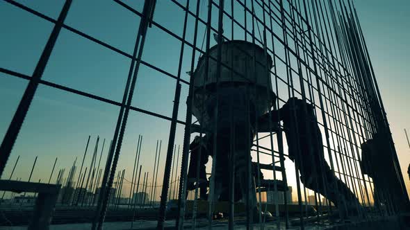 Sunset Building Site with Workers Handling a Concrete Barrel. Construction Industry, Construction alt