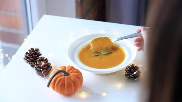 Woman eating pumpkin soup on a table