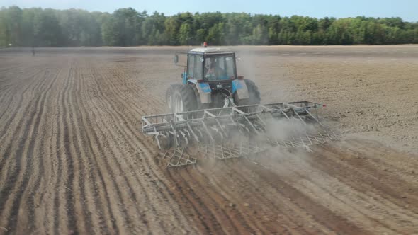 Aerial top view of a tractor, combine harvester plowing agricultural land in the spring