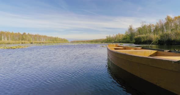 Old Wooden Rowing Fishing Boat Moored Near Lake Or River Coast In Beautiful Autumn Sunny Day alt
