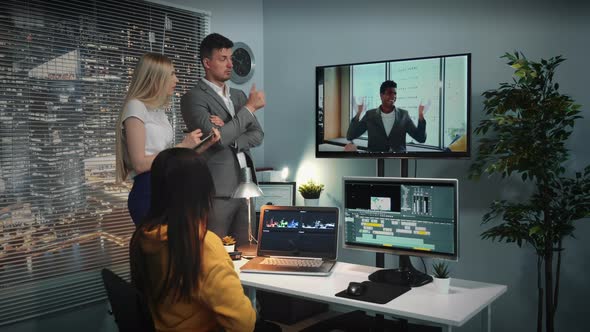 Mixed Race Team of Video Editors Listening To Chief Commenting Video Watched on Big Screen alt