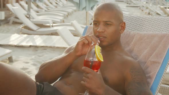 Handsome African Man Drinking Cocktail While Relaxing at the Beach