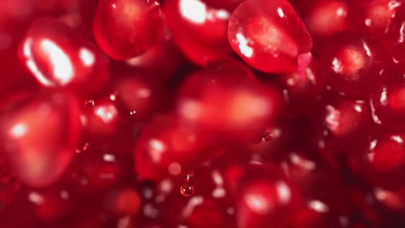 Pomegranate Grains Rolls Down on Surface of Broken Pomegranate in Slow Motion alt