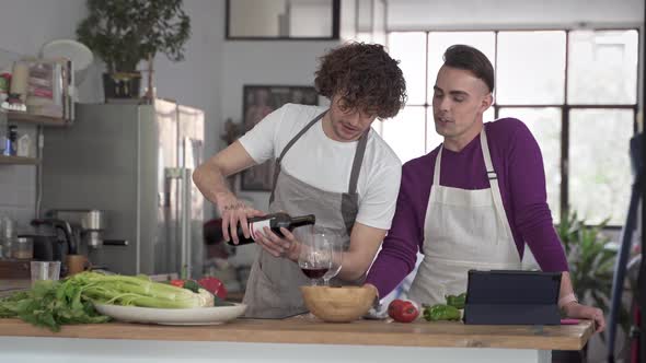 Happy Gay Couple Having Fun at Home Drinking and Cooking Together in the Kitchen alt