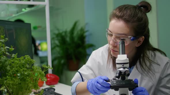 Biologist Scientist Looking at Green Leaf Sample Under Microscope alt