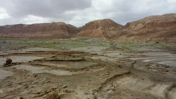 Dead sea desert green after the rain, fly over, red mountain background, cloudy sky, drone shot alt