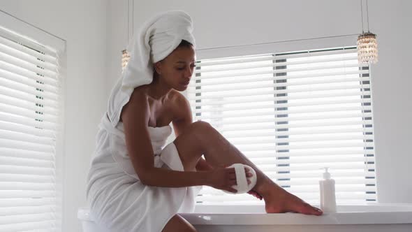 African american woman using loofah while taking a bath in bathroom alt