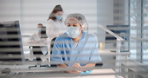 View Through Window with Blinds of Modern Hospital Office with Doctors in Mask Working alt