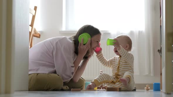 Little Baby Girl and Mommy Play with Colorful Toys at Home Sitting on Floor alt