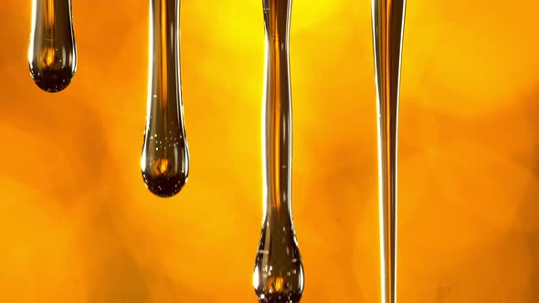 Super Slow Motion Macro Shot of Dripping Oil on Golden Background at 1000 Fps alt