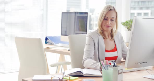 Businesswoman working over computer at her desk alt