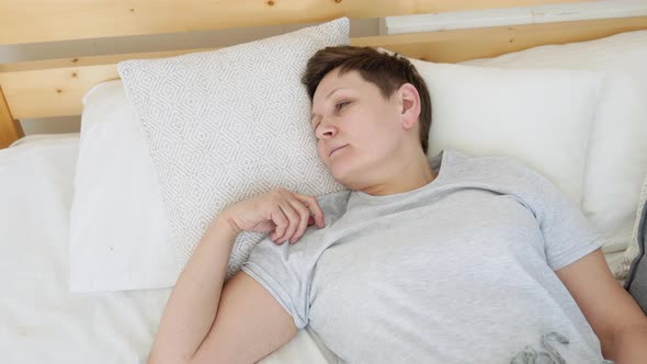 Mature Woman Falls Asleep in a Cozy Bed alt