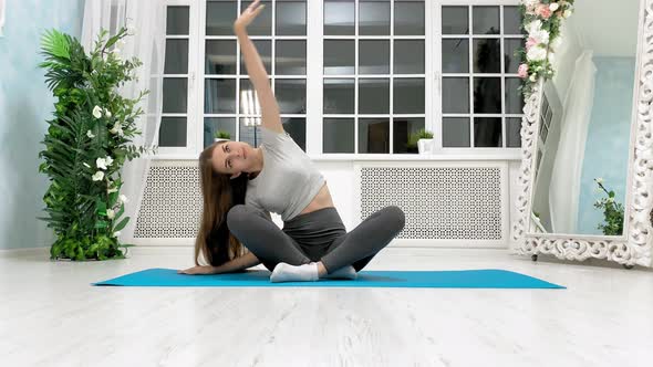 Beautiful  fitness girl in athletic workout clothes is doing yoga at home