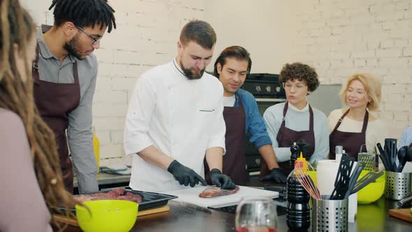 Professional Chef Cutting Meat During Culinary Master-class in Cookery School alt