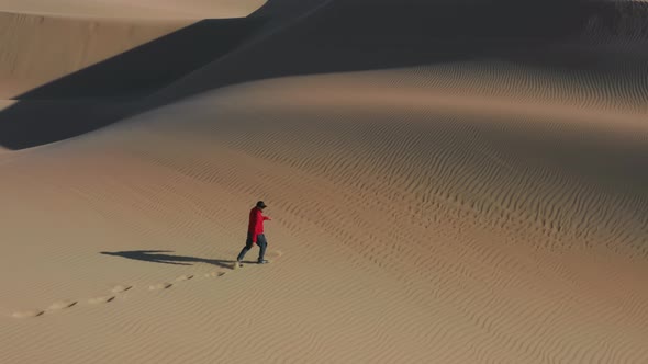 Man Energetically Running Up Dunes Creating Golden Clouds of Sands at Sunset alt