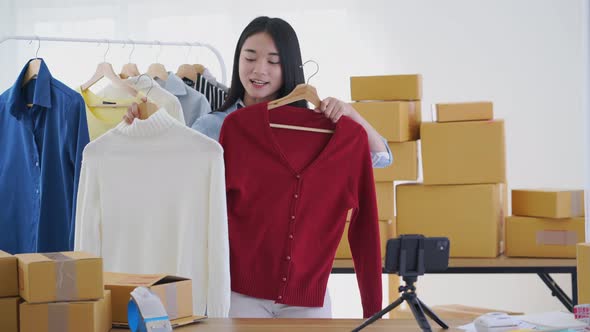 Young Asia woman selling fashion clothes two color online by live with smartphone	