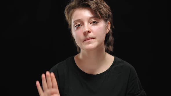 Closeup Portrait of Scared Abused Young Woman Looking Around and Showing Sign to Help Palm at Camera alt