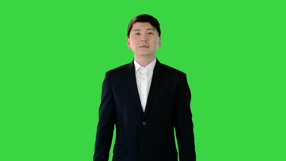 Asian Man Stands Adjusting His Suit and Crossing Arms on a Green Screen Chroma Key