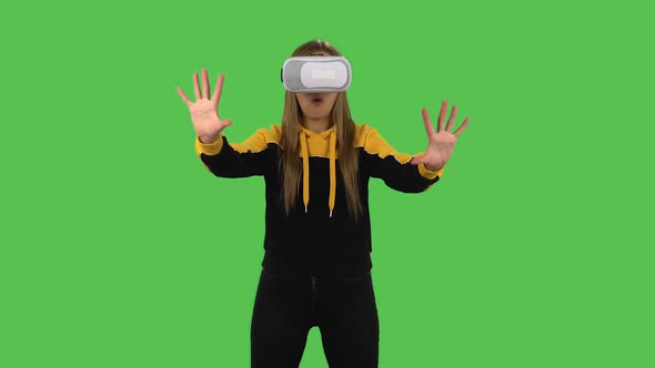 Modern Girl in Yellow Hoodie with Virtual Reality Headset or 3d Glasses. Green Screen alt