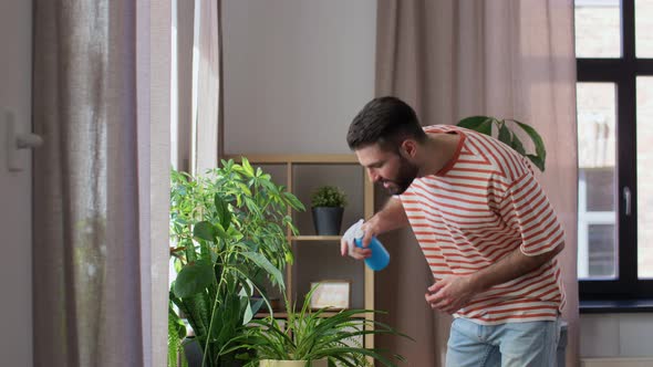Happy Man Spraying Houseplant with Water at Home