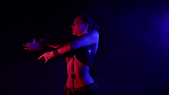 An Attractive Woman Is Dancing an Oriental Dance on a Black Smoky Background in the Studio Making alt