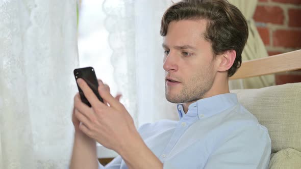 Portrait of Young Man Celebrating Success on Smartphone alt