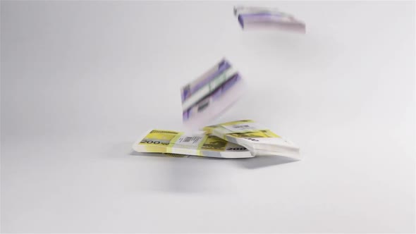 Few Euro Money Bundles Dropping at White Surface alt
