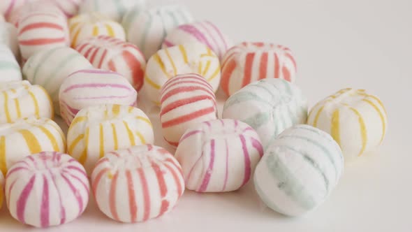 Tilting on retro striped round candies on white 4K footage alt