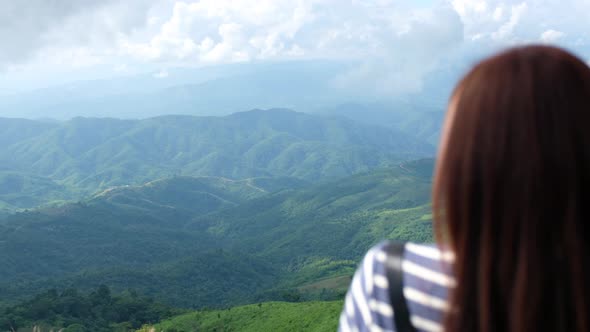 Rear view of a female traveler looking at a beautiful green mountains view